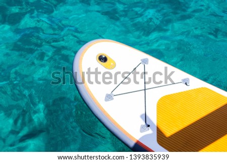 surfing board on bright aquamarine tropic water background surface, summer activity and sport concept picture, wallpaper pattern with empty copy space for text 