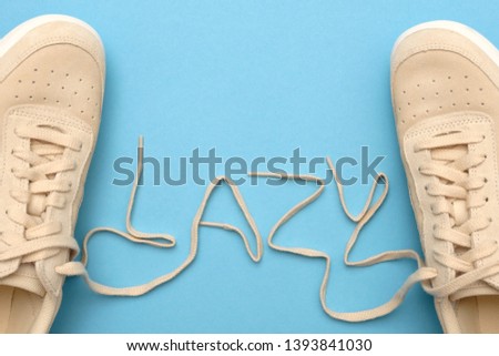 New women sneakers with laces in lazy text. Flat lay on blue background.