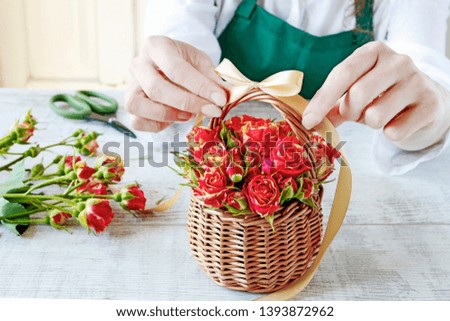 Florist at work: Woman shows how to make a floral arrangement with roses inside the wicker basket. Mother's day gift, step by step, tutorial. 