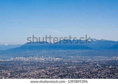 Horizontal of Vancouver, British Columbia, viewed from the air on a hazy, sunny day with the Rockies in the background