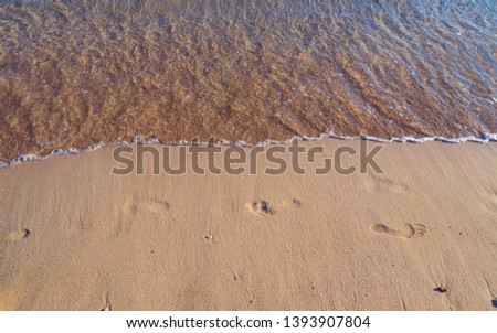 Footprints on a empty sandy beach - small waves approaching