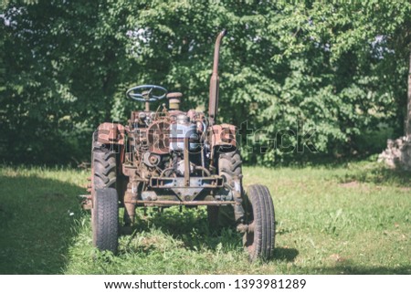old tractor with rubber tires in green countryside yard in green summer time - vintage retro film look