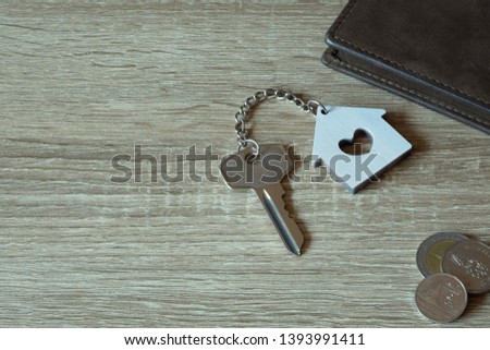 House key with home keyring and wallet on wood table, copy space