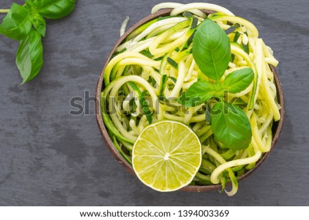 Close up green raw zucchini spaghetti with lime and basil, helathy food concept 