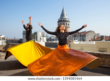 Whirling Dervishes or Semazen in Istanbul, Turkey. Galata Tower and city in background. Male and female dervish together 
