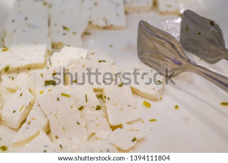 Sliced herby cheese with metal tongs                          Royalty-Free Stock Photo #1394111804