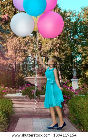 Pretty young girl with big colorful balloons walking in the park - image. Air balloons. Holiday party, birthday. 