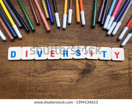 Diversity - word spelled with letter pieces on the table covered with colored markers. Copy space. Social problems concept 