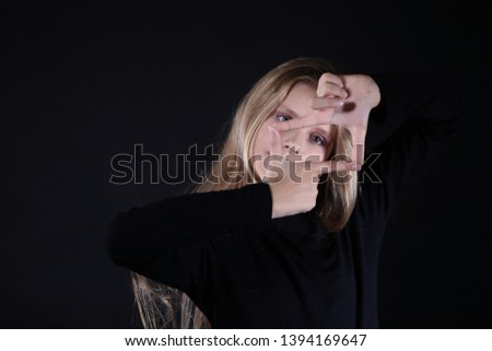 Portrait of a blonde girl with long hair on a black background. Emotional portrait.The girl shows different emotions on the face. Plays with long hair.Child portrait concept.