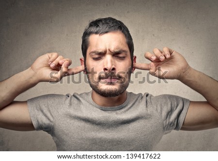 portrait of young man holds his hands over his ears not to hear Royalty-Free Stock Photo #139417622
