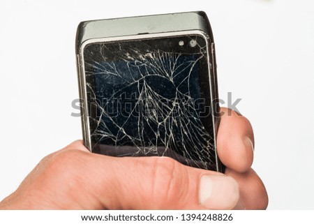 Male hand is holding a broken cell phone. Broken touch screen in man's hand. Cracked, damaged phone. human hand.