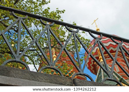 Multicolored domes of St. Basil's Cathedral in Moscow Russia through the lattice of the black fence