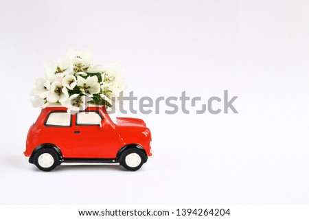 Red ceramic car with flowers on the roof on white background. February 14 card, Valentine's day. Flower delivery.