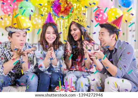 Picture of young people celebrating a birthday party at home with colorful balloons and confettis