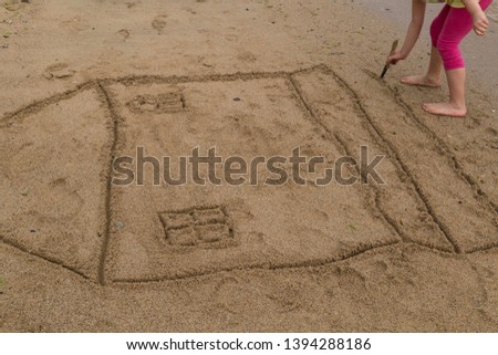 the child draw house picture on the sand at the beach by the sea in the summer for holiday concept.