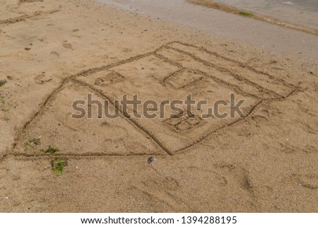 the child draw house picture on the sand at the beach by the sea in the summer for holiday concept.