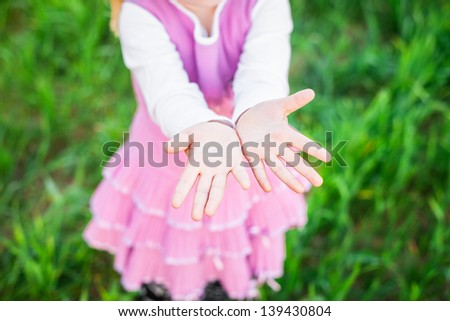 Little girl showing a palm in green wheat field