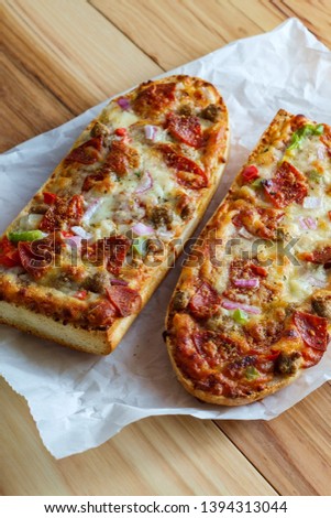 Supreme French bread pizza with pepperoni sausage black olives red onion and green bell pepper toppings