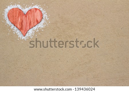 Handmade red heart in the sand with copy space.