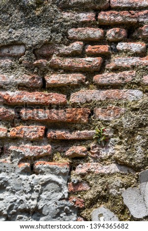 Old weathered masonry wall with crumbling brick and many cement patches, as a textured background
