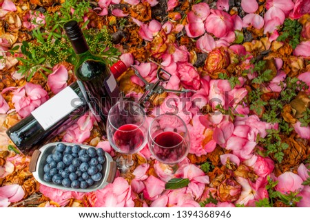 bottles, wine glasses with blueberry in rose garden.