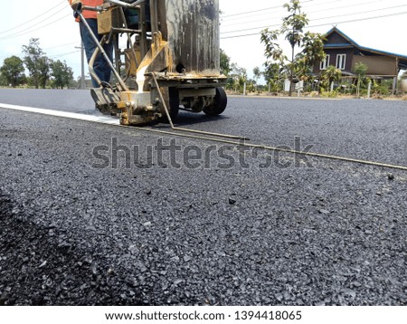 Technicians are working on white traffic lines on the asphalt surface.