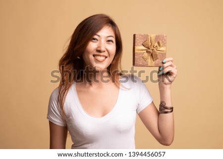 Young Asian woman with a gift box on beige background