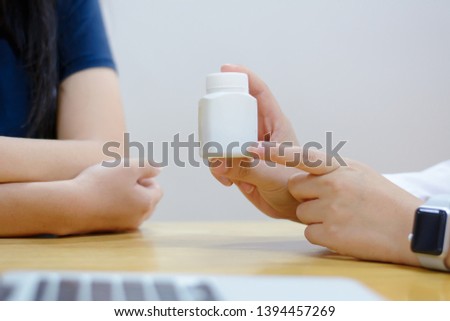female medicine doctor  holding jar of pills and explains to the patient