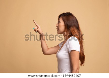 Asian woman touching the screen with her finger on beige background