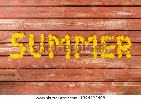 Word summer from yellow dandelions on old wooden background. Top view, flat lay, copy space.