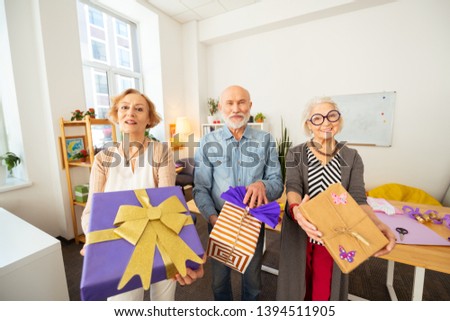 beautiful. Joyful elderly people smiling while showing you their gifts