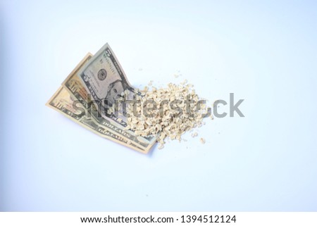 banknotes in denominations of five and ten dollars and oatmeal is poured on them on a white background