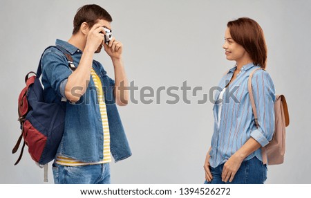 travel, tourism and vacation concept - happy couple of tourists with backpacks and film camera photographing over grey background