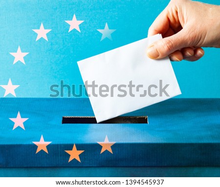 european Union parliament election concept - hand putting ballot in blue election box - EU flag
