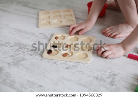 Hands of a child playing in wooden colored cubes, puzzles on a white wooden background close-up.