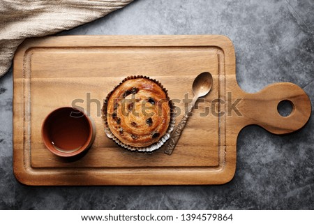Raisin Danish pastry on wooden plate and stone background