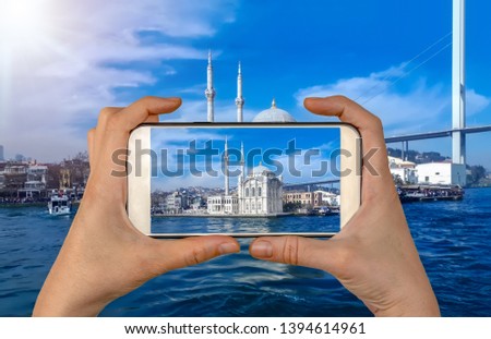 Tourist taking a picture in front of  Ortakoy mosque and Bosphorus bridge, Istanbul, Turkey. Travel concept 