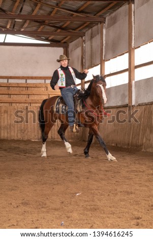 A cowboy in a hat on a horse shows a performance in the sand in the arena
