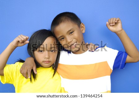 Happy laughing couple making Victory of hand gesturing on blue background 