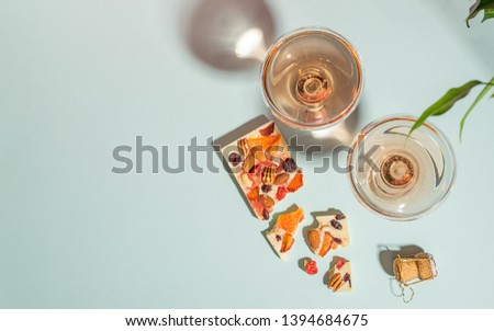 Drink champagne or wine in two elegant glasses and a bar of white chocolate gentle blue background. Concept minimalism.