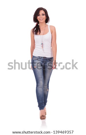 full length picture of a casual young woman walking straight toward the camera with a smile on her face. on white background