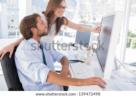 Photo editors looking at computer screen with one pointing in modern office Royalty-Free Stock Photo #139472498