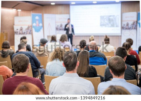 Speaker giving a talk in conference hall at business event. Audience at the conference hall. Business and Entrepreneurship concept. Focus on unrecognizable people in audience.