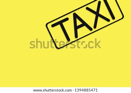 Word taxi in frame of black color cut out of black paper on yellow background. Top view. Concept of journey. Copy space