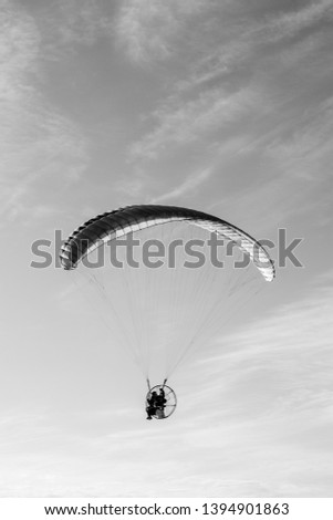 Motorized paragliding in the clouds, black and white photography. Concept of freedom.