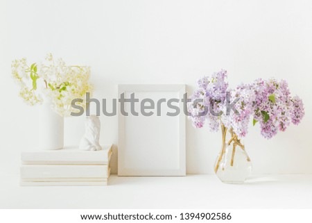 Home interior with decor elements. White frame, branches of lilac in a vase, interior decoration
