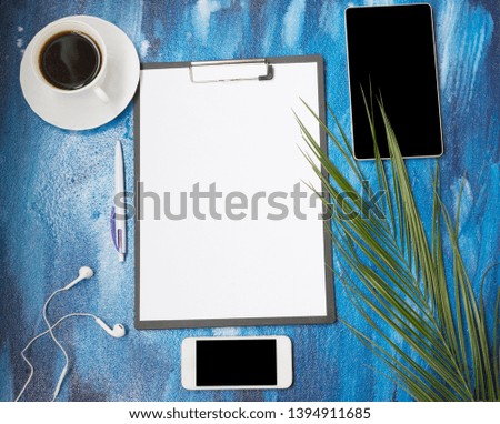 Tropical palm leaves, phone, camera, tablet,  headphones and coffee on a blue background. Flat lay, top view. Copy Space, using for business background