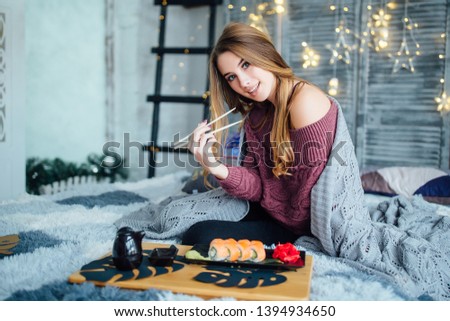 Young beautiful woman holding asian chopsticks at home with happy face .