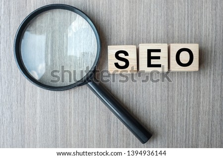 SEO (Search Engine Optimization) text wooden cubes and magnifying glass on wood table background. Idea, Vision, Strategy, Analysis, Keyword and Content concept