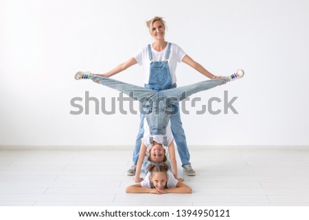 people, family and sport concept - young mom with twins daughters doing exercises on white background